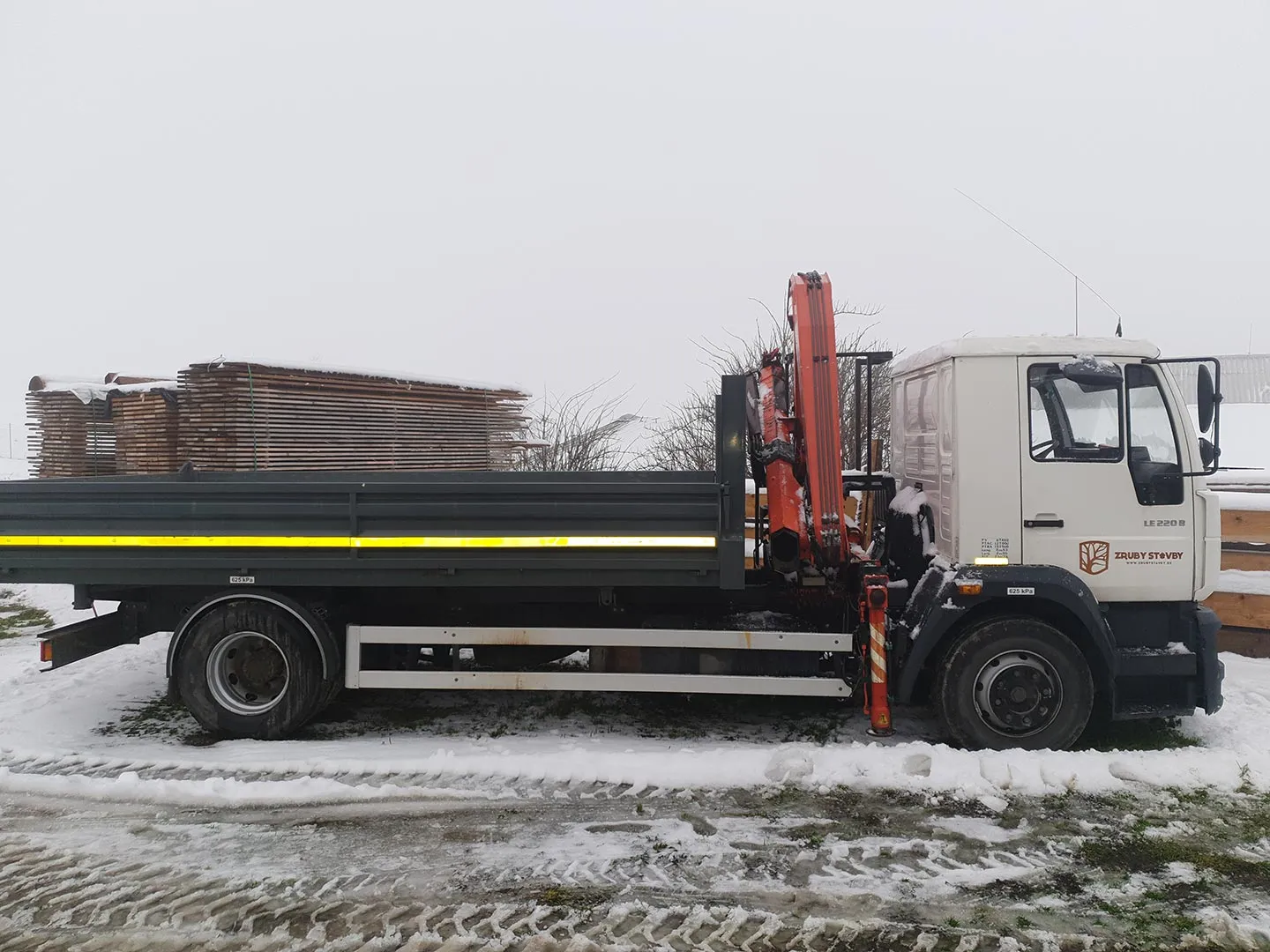 Nákladné auto s hydraulickou rukou naložené drevom